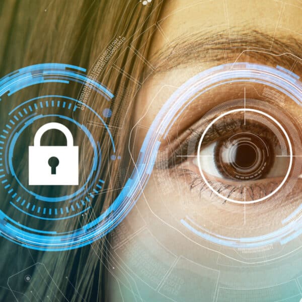 Close-up of a woman's eye with digital graphics overlay. On the left, there is a lock icon enclosed in a security circle, suggesting biometric access or security. Holographic interface designs surround the eye, indicating advanced biometric technology.