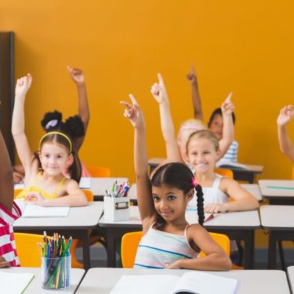 School kids raising hand in classroom