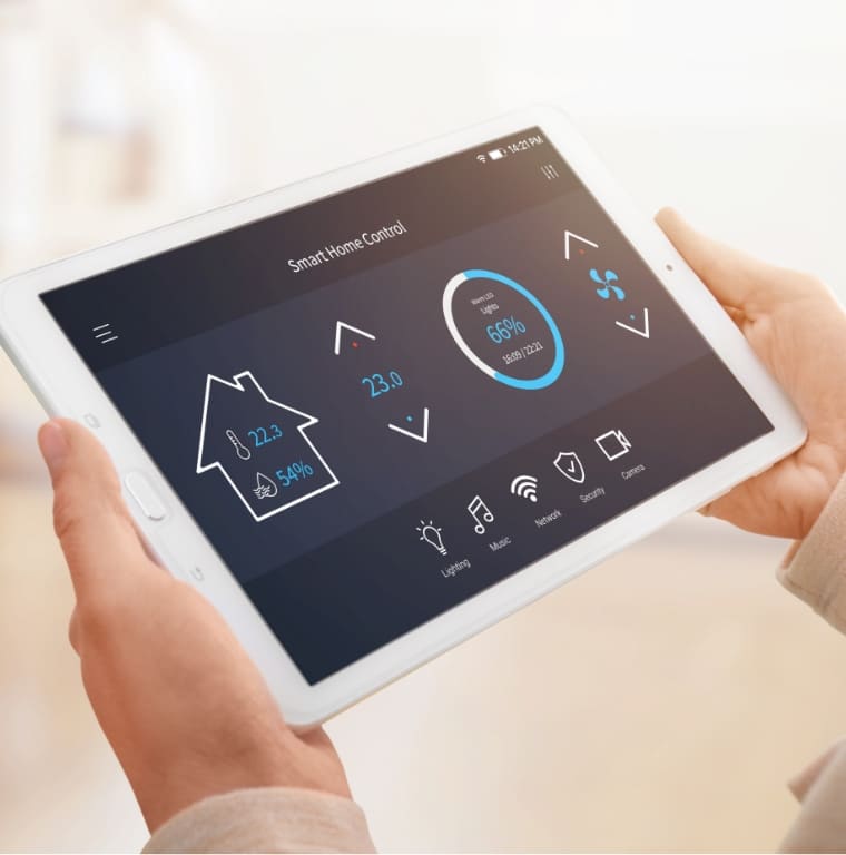 A person holds a tablet displaying a smart home control interface. The screen shows various controls for lighting, music, security, and climate, including the temperature and humidity levels, as well as fan and heating options.